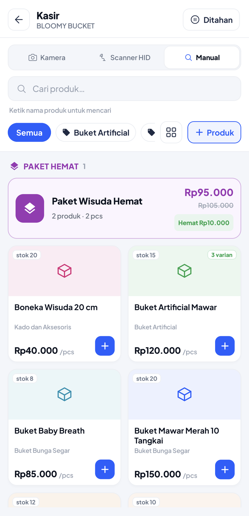 Layar Kasir Bloomy Bucket: pilihan Kamera, Scanner HID, Manual; kolom Cari produk; filter kategori Semua dan Buket Artificial; tombol + Produk; kartu Paket Wisuda Hemat Rp95.000 dari Rp105.000 hemat Rp10.000; lalu kartu produk Boneka Wisuda 20 cm, Buket Artificial Mawar 3 varian, Buket Baby Breath, dan Buket Mawar Merah 10 Tangkai beserta stoknya